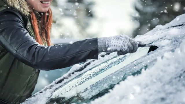 Frau kratzt vereiste Scheibe frei