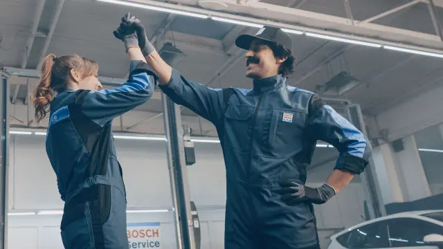 Mechaniker in der Werkstatt geben sich einen Handschlag