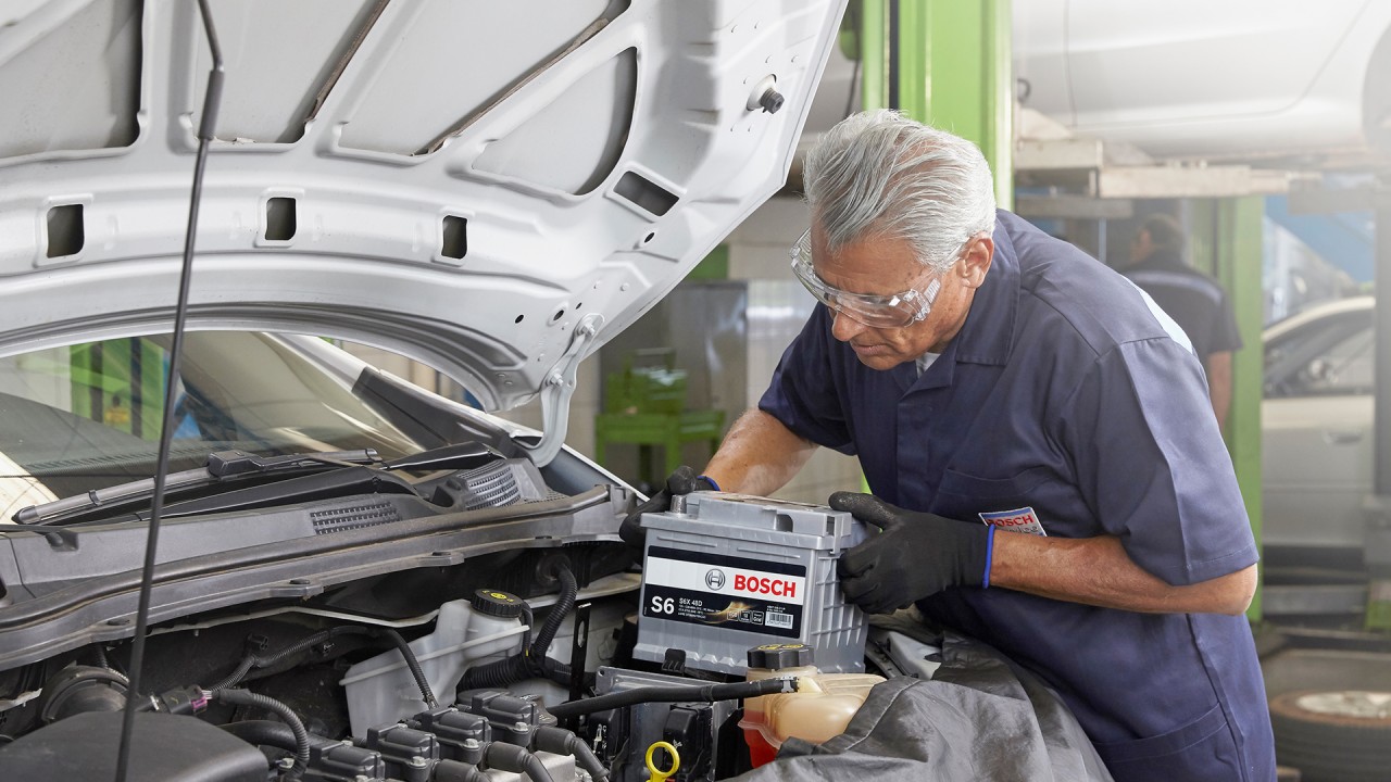 Usta otomobilin motor bölümünde akü değiştiriyor