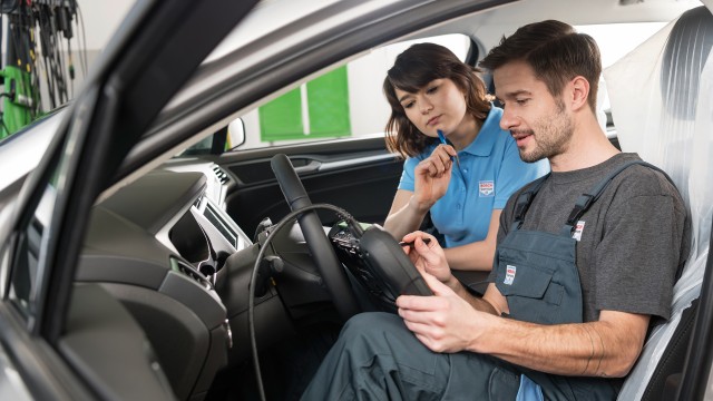 Inspektion: Zwei KFZ-Mechaniker untersuchen Elektronik in Auto